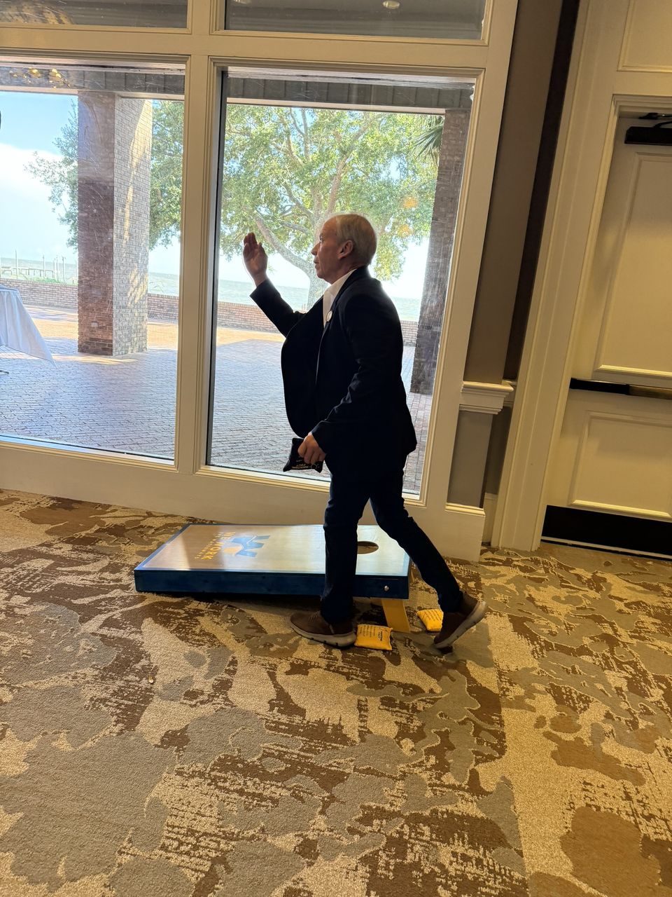An attendee tosses a bean bag in a game of cornhole.