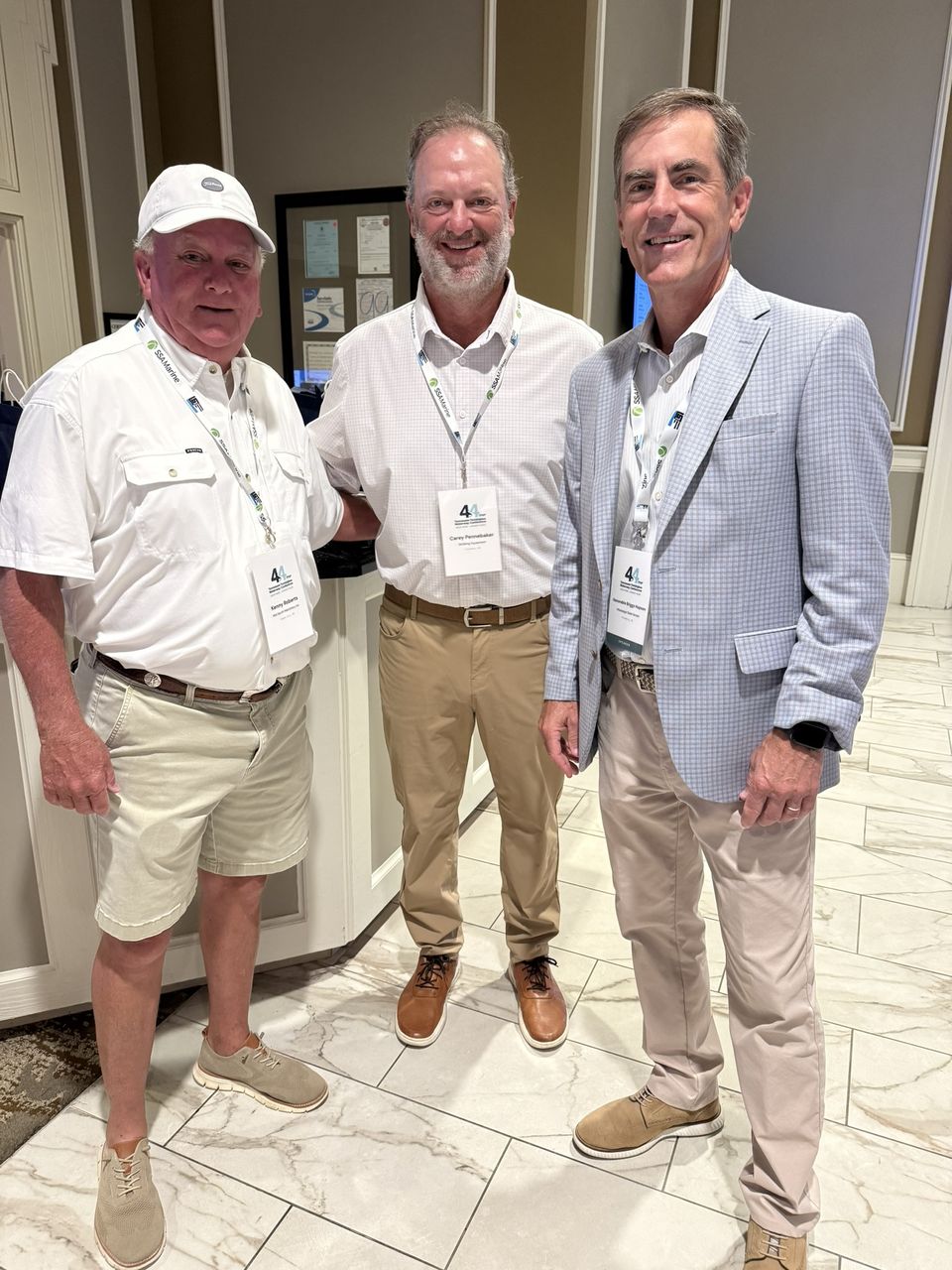 Three attendees pose in the hotel lobby.