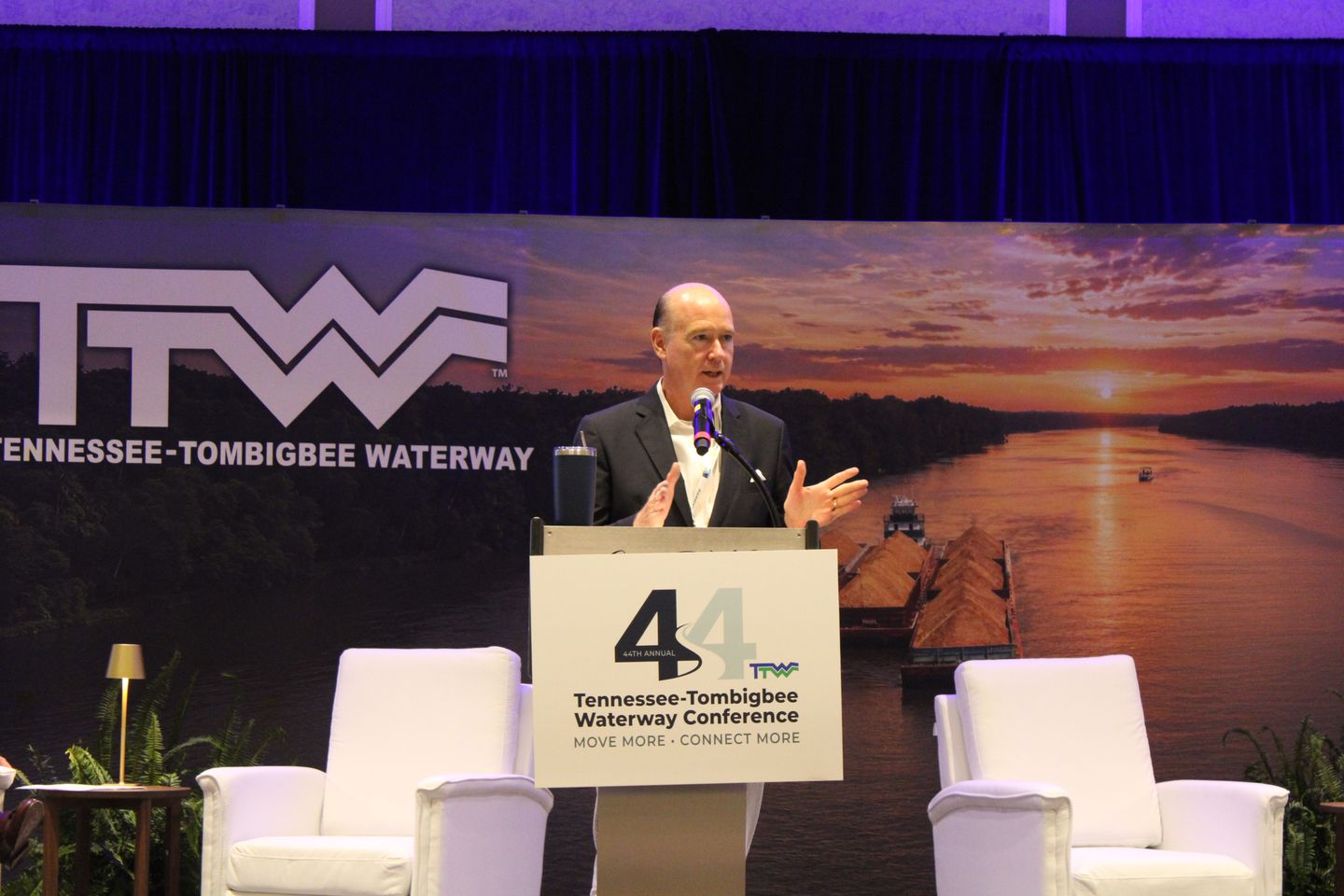 A speaker at the podium on the main stage, below the Tennessee-Tombigbee Waterway logo.
