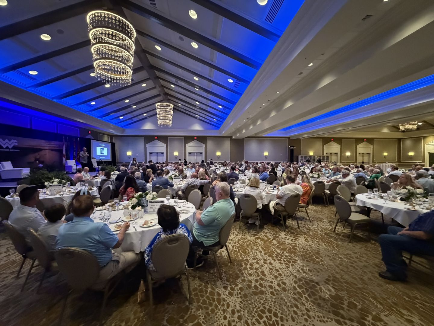 The banquet ballroom full of dinner tables under chandeliers.