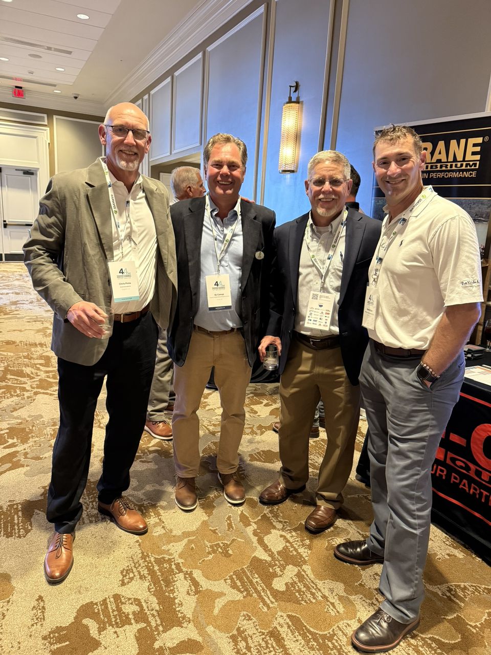 Four attendees pose at an exhibitor booth.