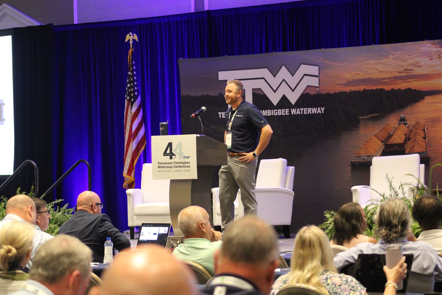 A speaker addresses a full room from the stage.