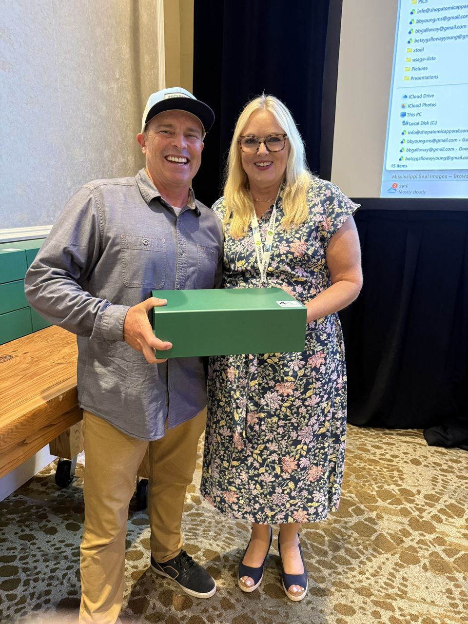 A man and a woman smile with a green gift box.