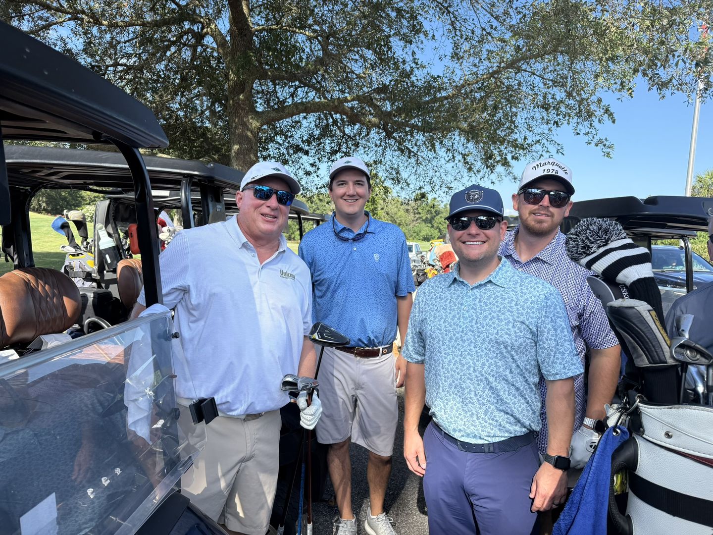 A golf foursome poses beside their carts.