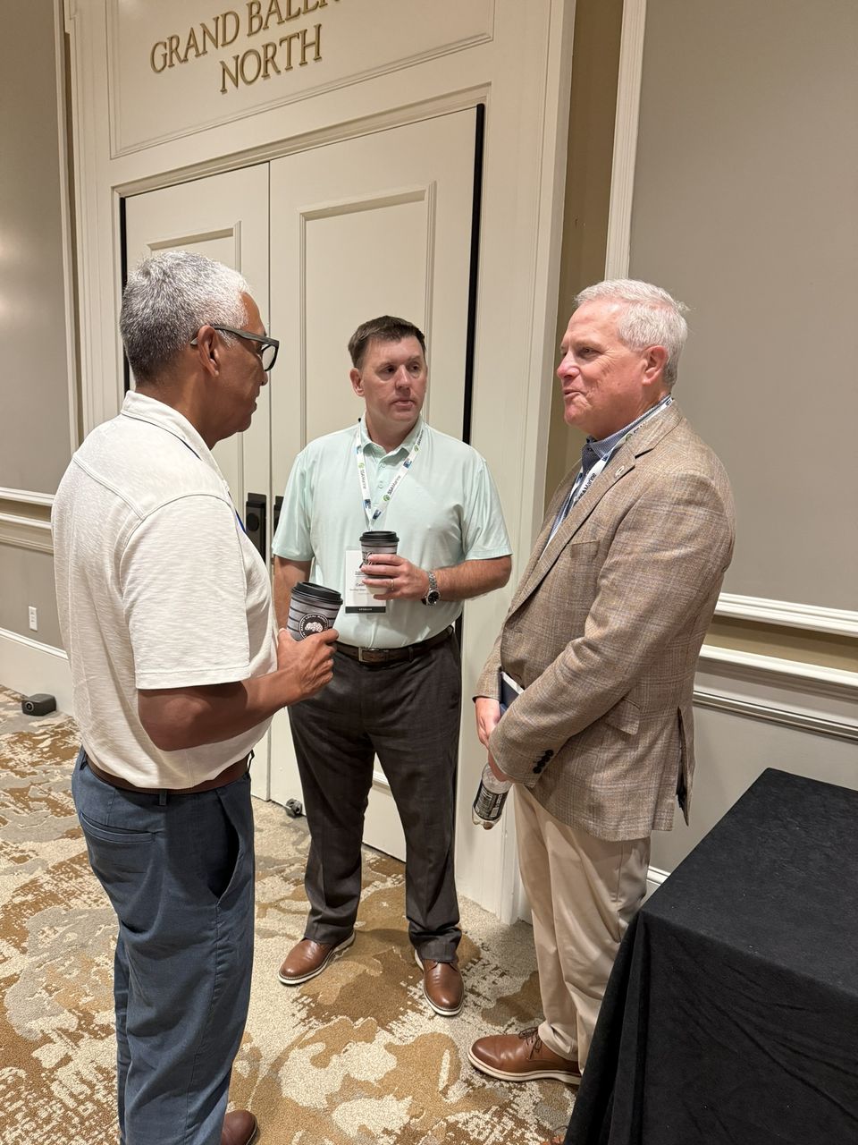 Three attendees talk outside the Grand Ballroom.