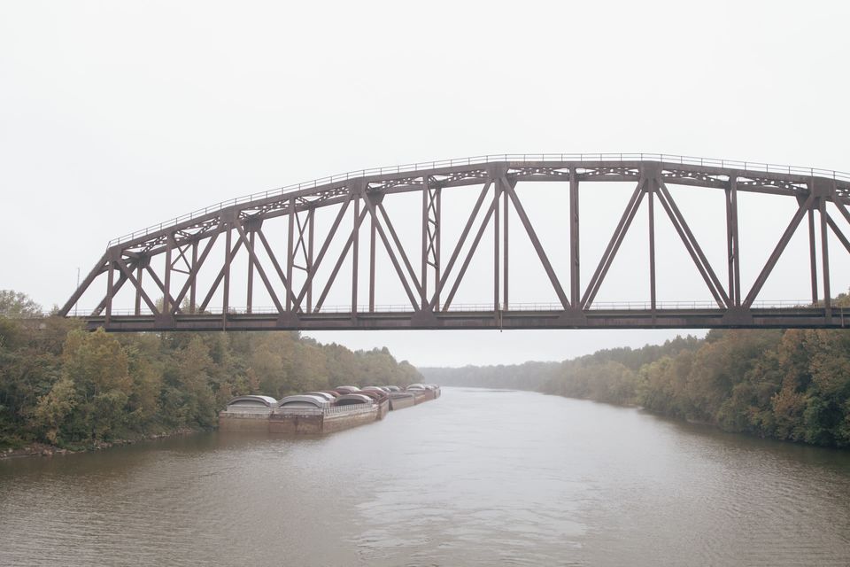 A steel truss bridge spans the waterway in golden evening light.